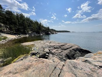 Scenic view of rocks on shore against sky