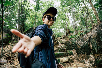 Young man wearing sunglasses standing in forest