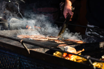 Cropped image of man preparing food on barbecue grill