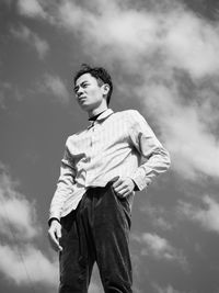 Low angle view of young man looking away against sky