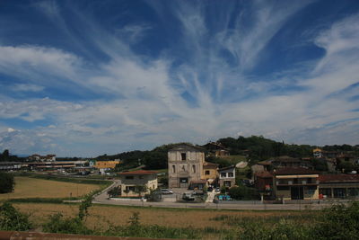 Houses on field by buildings against sky