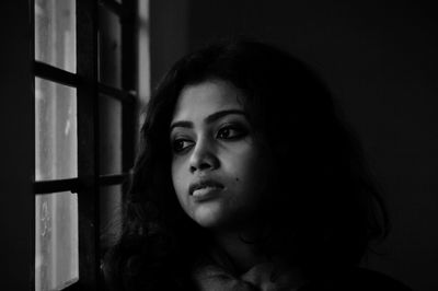 Beautiful young woman looking through window