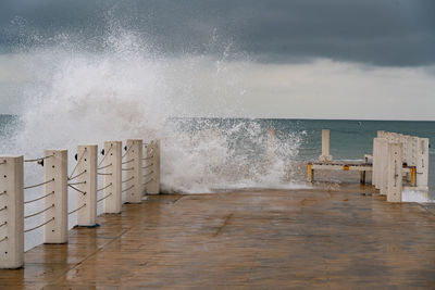 Sea waves splashing on shore against sky