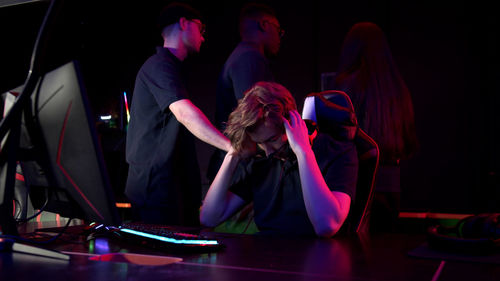 Man using computer by friends in darkroom