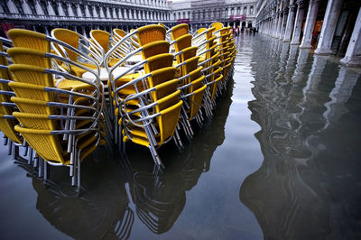 Yellow stacked chairs on water filled walkway during flood at piazza san marco