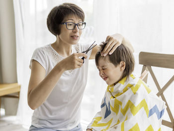 Mother trimming sons hair at home