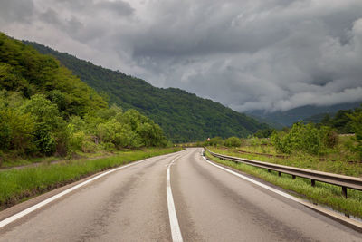 Road by mountains against sky