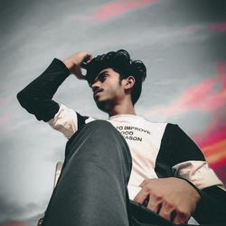 Low angle view of young man looking away against sky