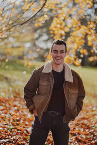 Portrait of young man standing on leaves during autumn