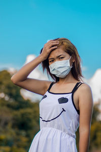 Portrait of beautiful young woman against blue sky