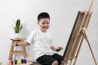 Side view of boy painting on canvas at home