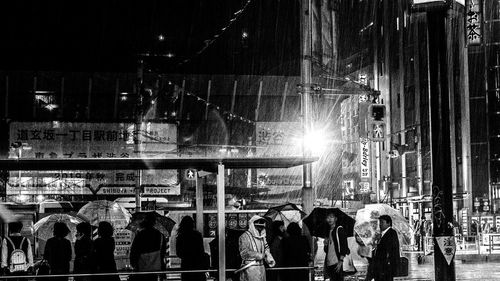 People walking on illuminated street in city at night