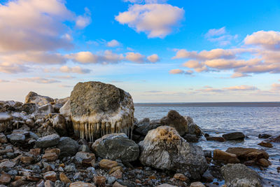 Rocks on beach against sky during sunset