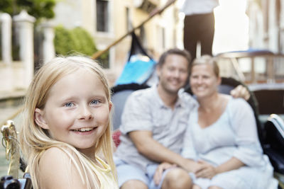 Girl on boat, parents on background