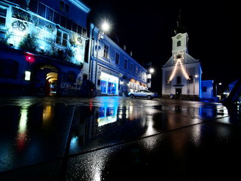 Reflection of illuminated building in puddle at night