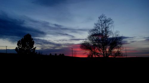 Silhouette trees on landscape against sky at sunset