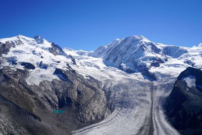 Scenic view of snowcapped mountains against clear blue sky