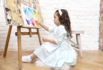 Cute girl drawing with a paint palette and a paintbrush. little painting artist.