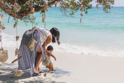 Side view of  women and baby on beach