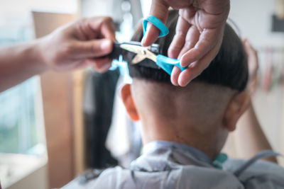 Asian child getting haircut at home. view from behind.