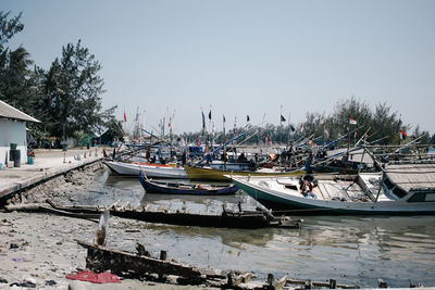 Boats moored at harbor against clear sky
