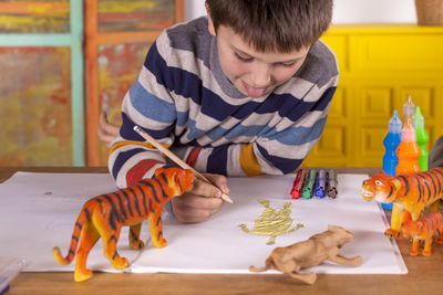 Boy sitting at a table drawing a tiger.