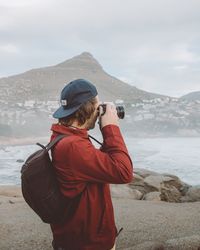 Rear view of man photographing sea against sky