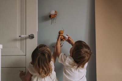 Rear view of people holding curtain at home