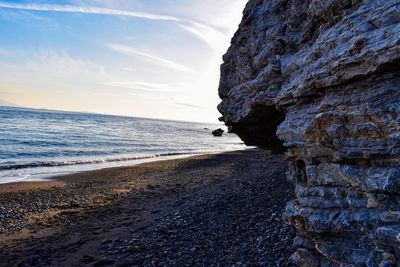 Rock formation on beach against sky during sunset