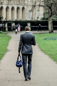 Rear view of man walking on footpath