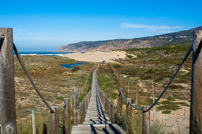 Footbridge over landscape against sky