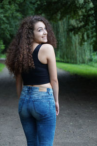 Portrait of beautiful woman looking over shoulder while standing on road