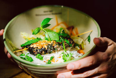 Close-up of hand holding salad in bowl