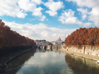 View of canal in city against cloudy sky