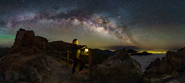 Women with illuminated lantern at scenic rock formation against sky at night