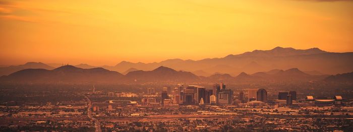 Illuminated cityscape against sky during sunset