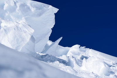 Low angle view of glacier against clear blue sky