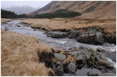 Scenic view of river by mountains against sky