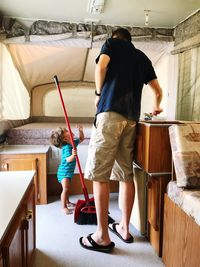 Full length of father and son cleaning bedroom