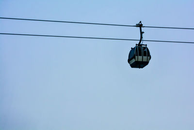 Low angle view of overhead cable car against clear blue sky