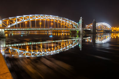 Illuminated bridge over river at night