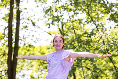 Portrait of young woman standing against trees