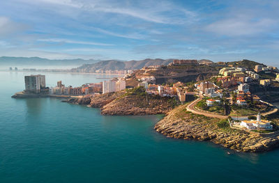 Aerial view of buildings in sea against cloudy sky