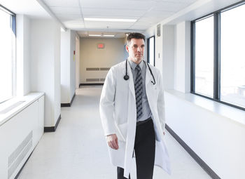 Doctor in a white coat walking down a hallway in a hospital.