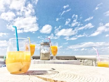 Close-up of drinks on table against sky during sunny day