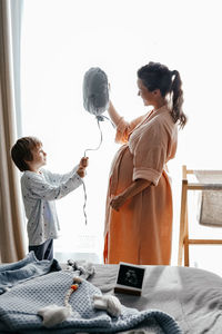 Side view of mother and daughter standing at home