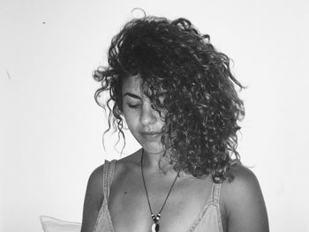 Close-up of young woman with curly hair against wall