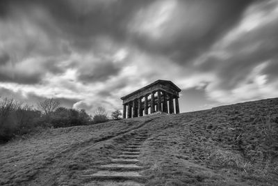 Built structure on hill against cloudy sky