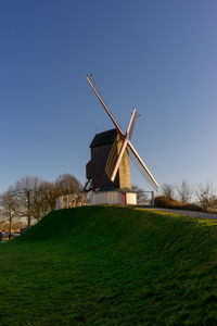 Traditional windmill on field against clear sky