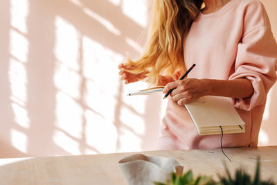 Midsection of woman reading book on table